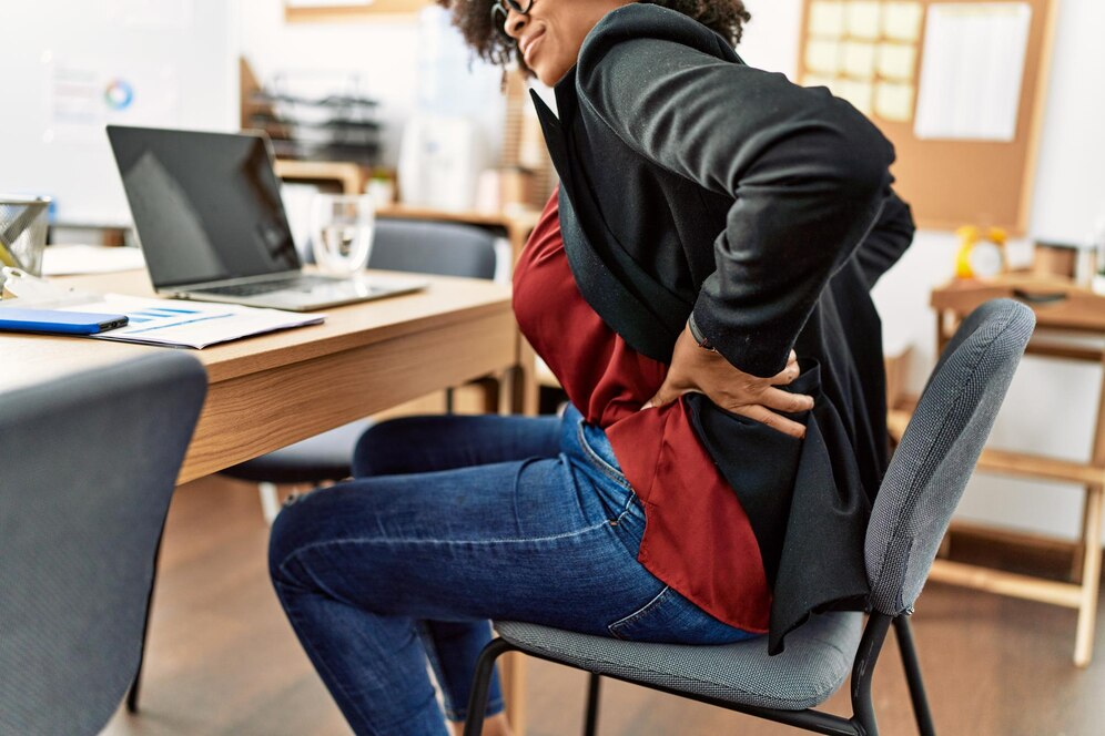 Mulher sentada com dores nas costas - ergonomia no home office