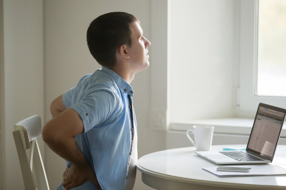 Homem jovem com dor nas costas no home office