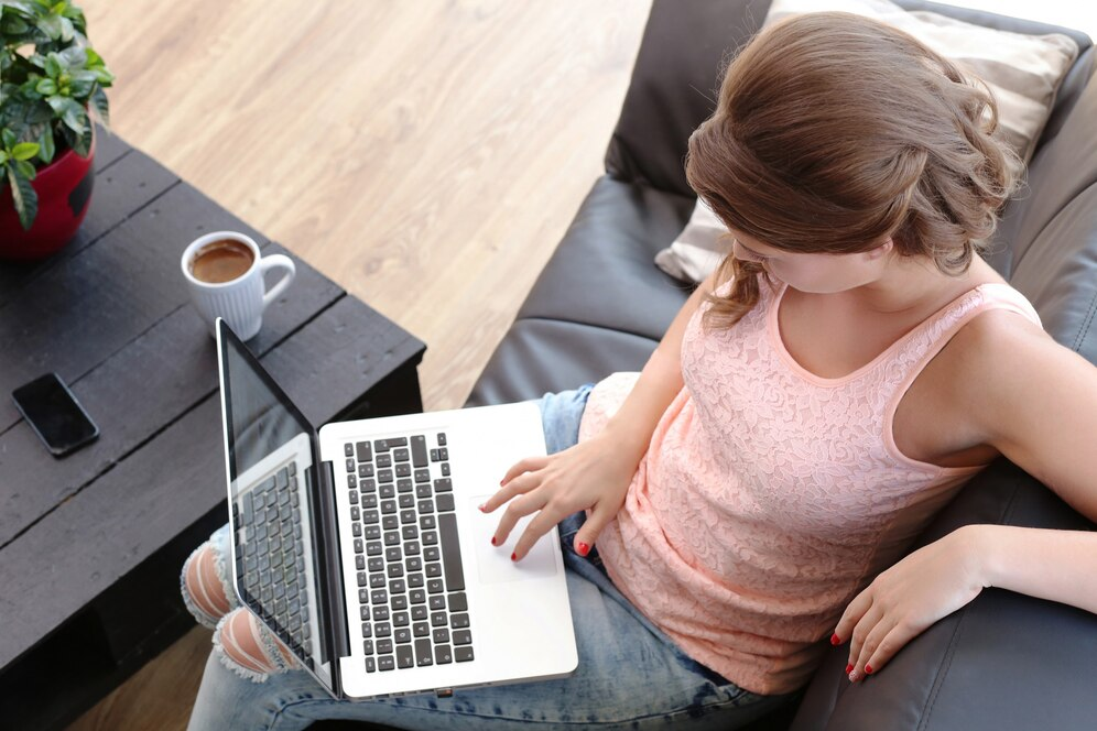 Mulher no sofá, usando o notebook - ergonomia no home office