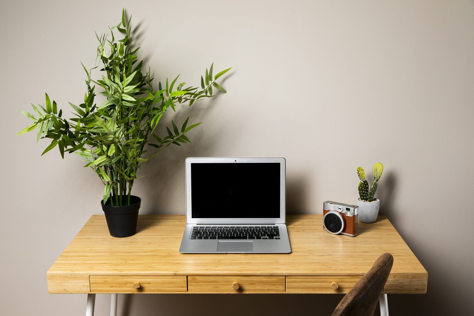 Escrivaninha pequena de madeira com notebook e planta sobre