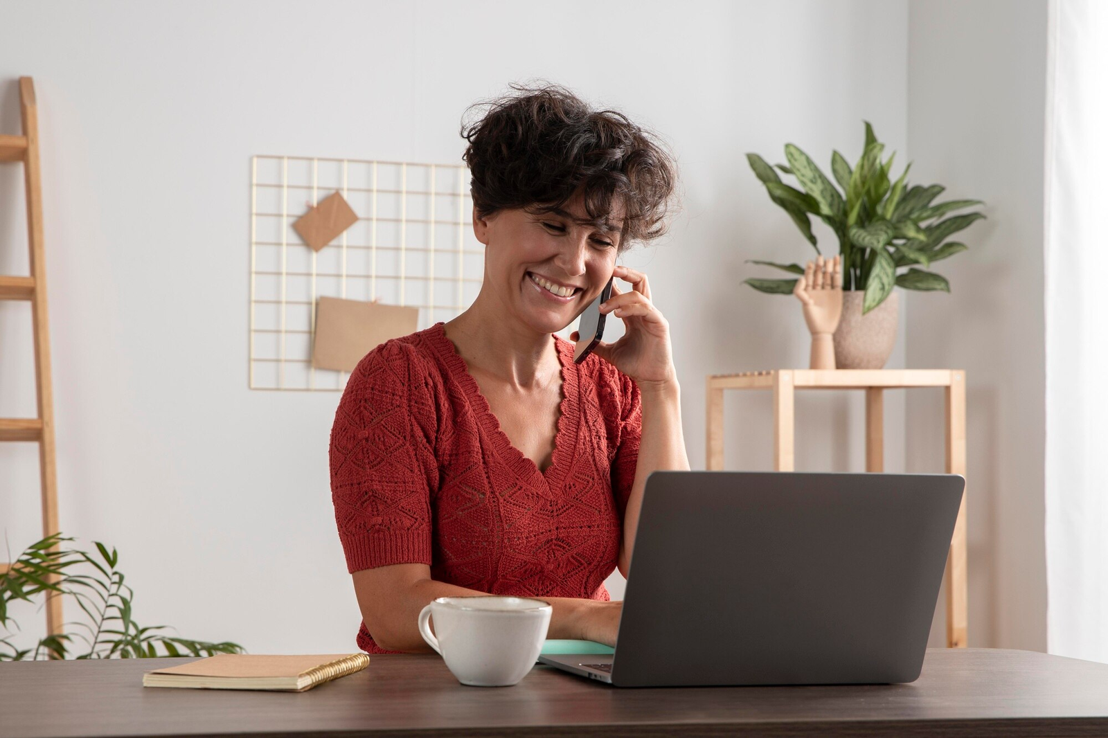 Mulher feliz no telefone trabalhando em home office