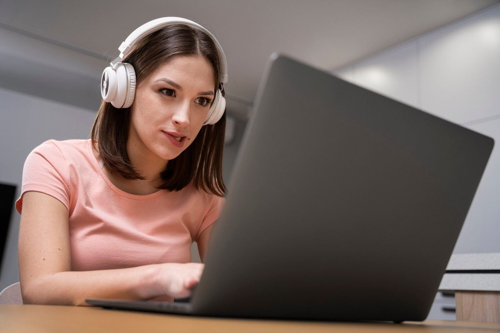 Garota gamer bonita jogando em notebook gamer usando headphone e com expressão de tensão