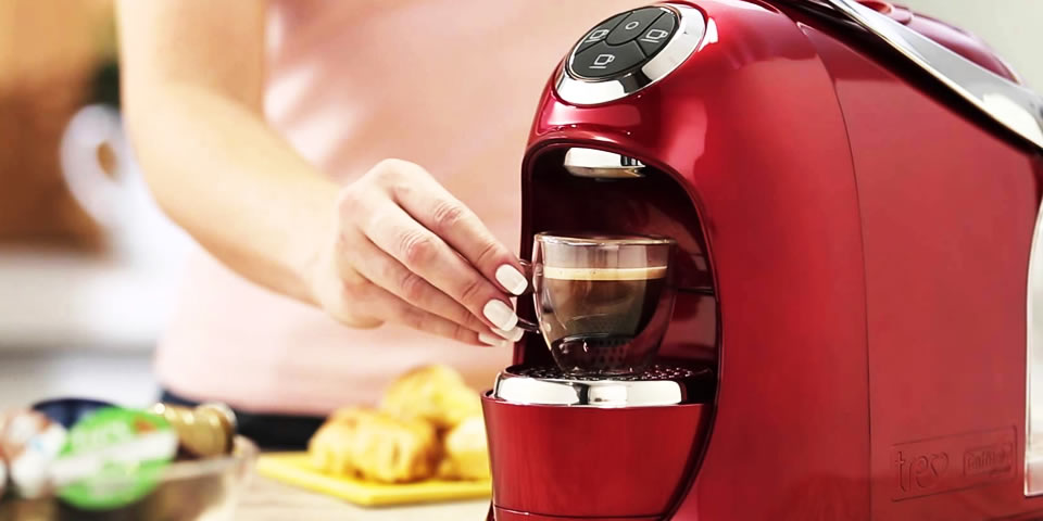 Mulher pegando xícara de café espresso na máquina TRES Versa